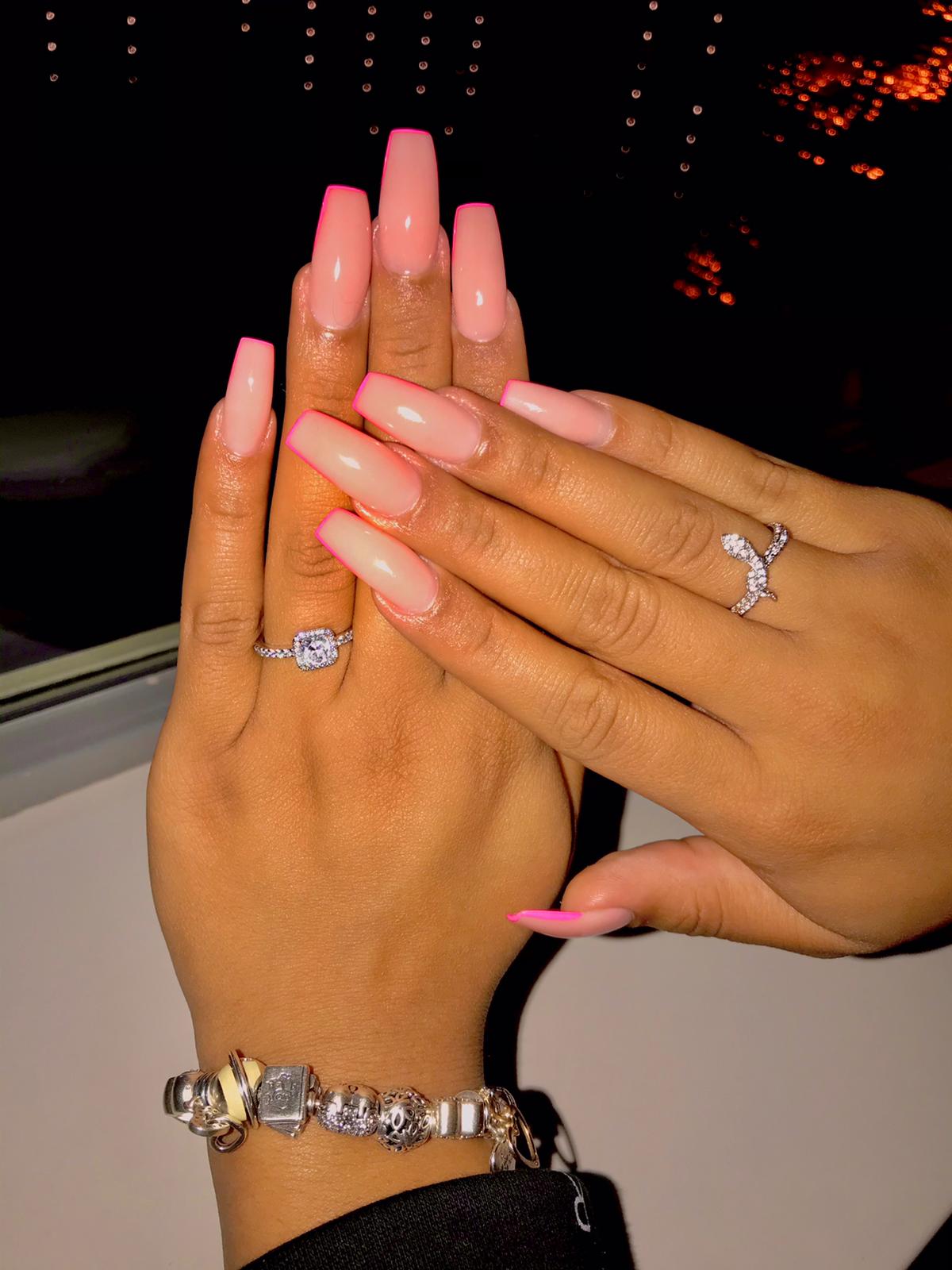 Lange roze-nude coffin nagels, twee handen tegen elkaar met ringen
