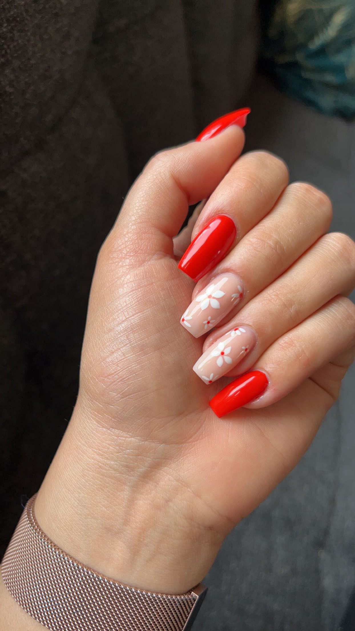 Rode nagels met twee nude accentnagels met bloemetjes