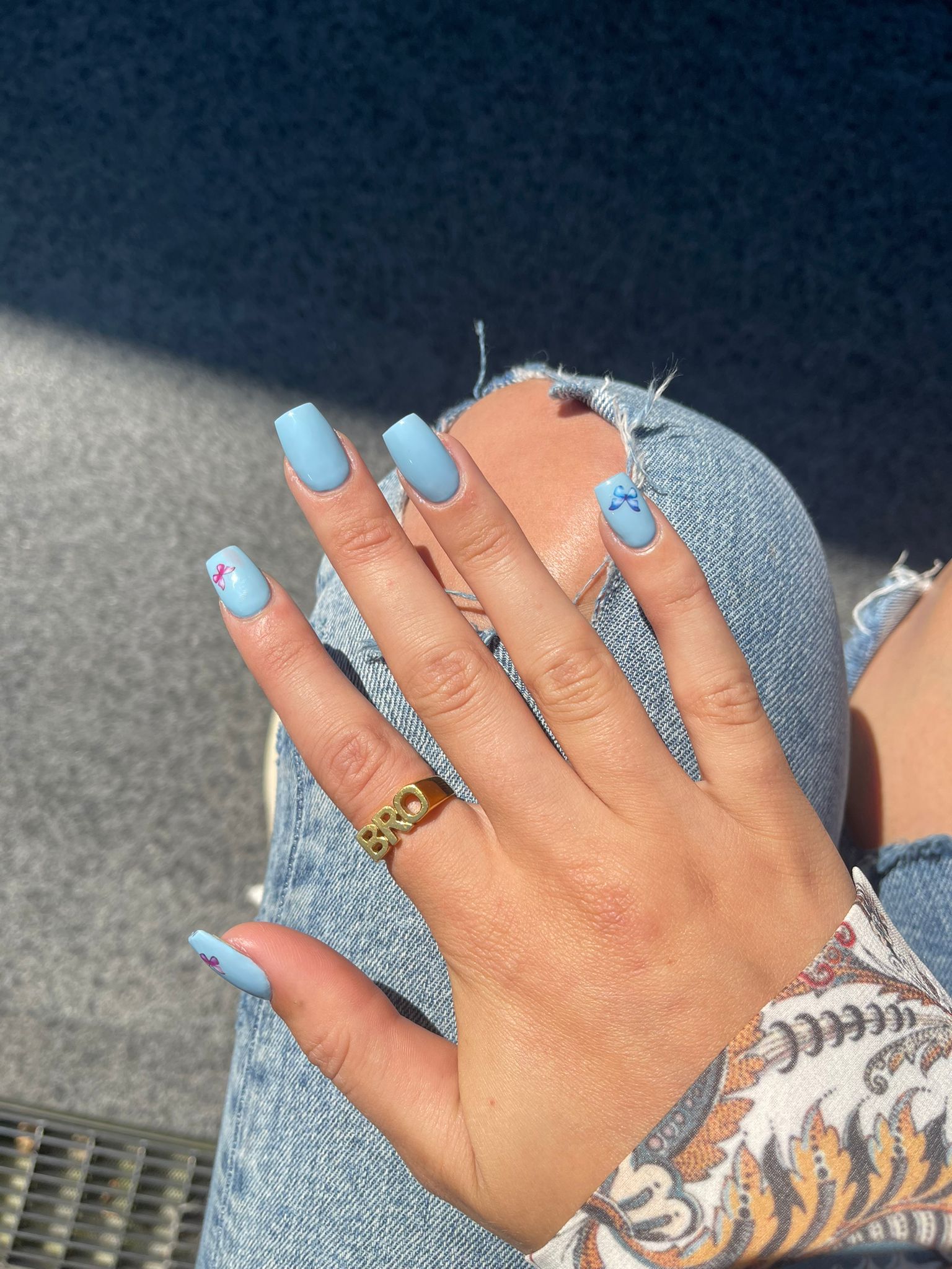 Lichtblauwe nagels met kleine nail art op een spijkerbroek